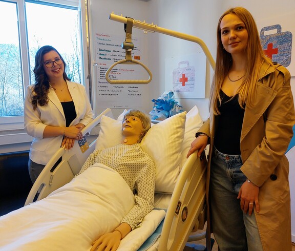 Zwei Schülerinnen über an einer Pflegepuppe