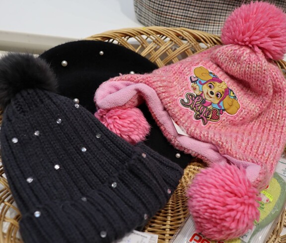 Eine schwarze perlenbesetzte Haube und eine rosa Kinder-Strick-Haube
