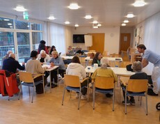 Ältere Menschen sitzen mit Computer und Smartphone an Tischen