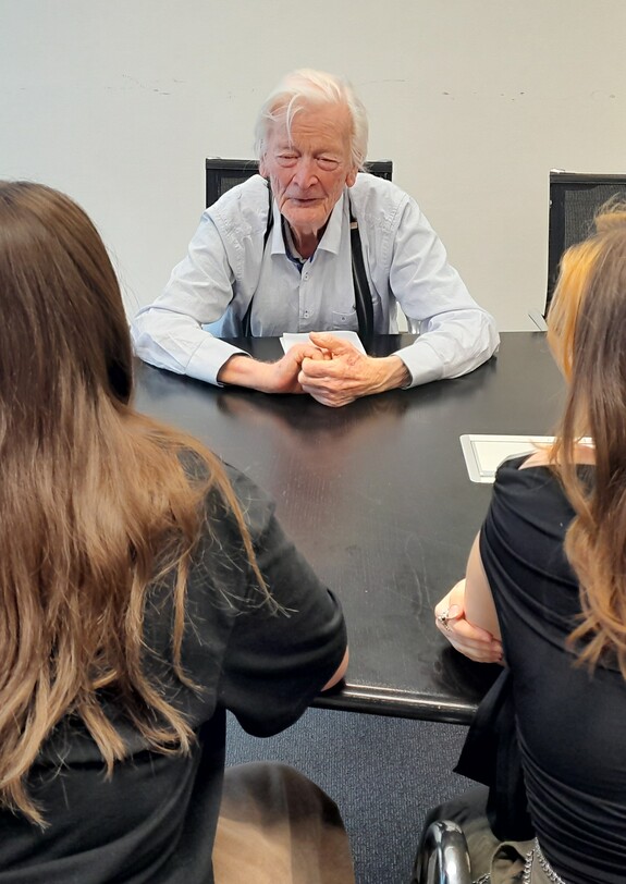 Ein alter Mann unterhält sich mit Schülerinnen