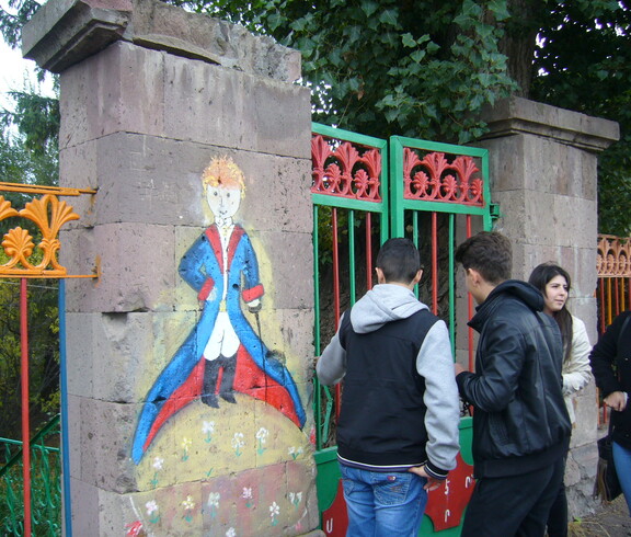 Jugendliche bemalen die Betonsäulen des Eingangtores eines Zentrums mit bunter Farbe.