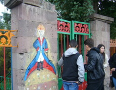 Jugendliche bemalen die Betonsäulen des Eingangtores eines Zentrums mit bunter Farbe.