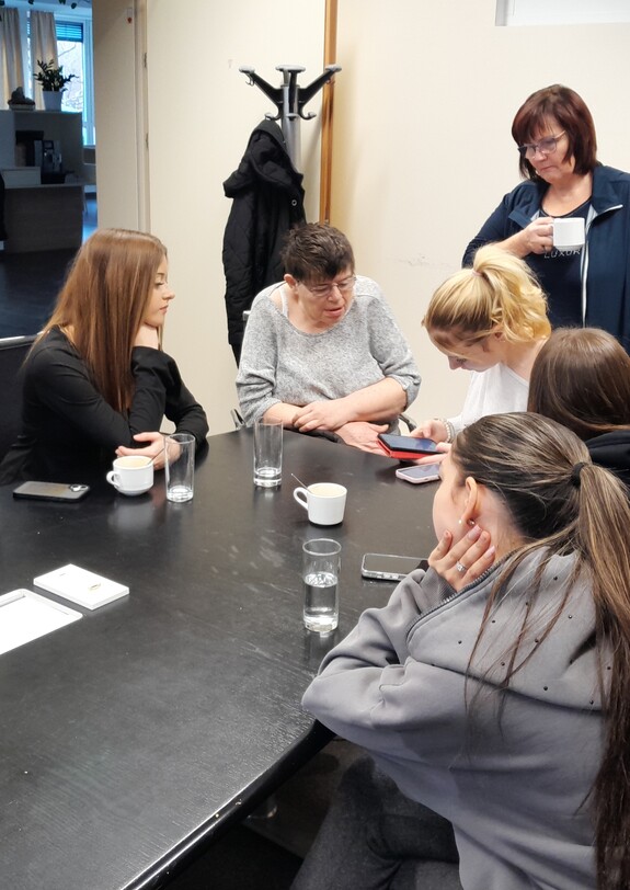 Menschen sitzen im Kreis an einem Tisch und diskutieren