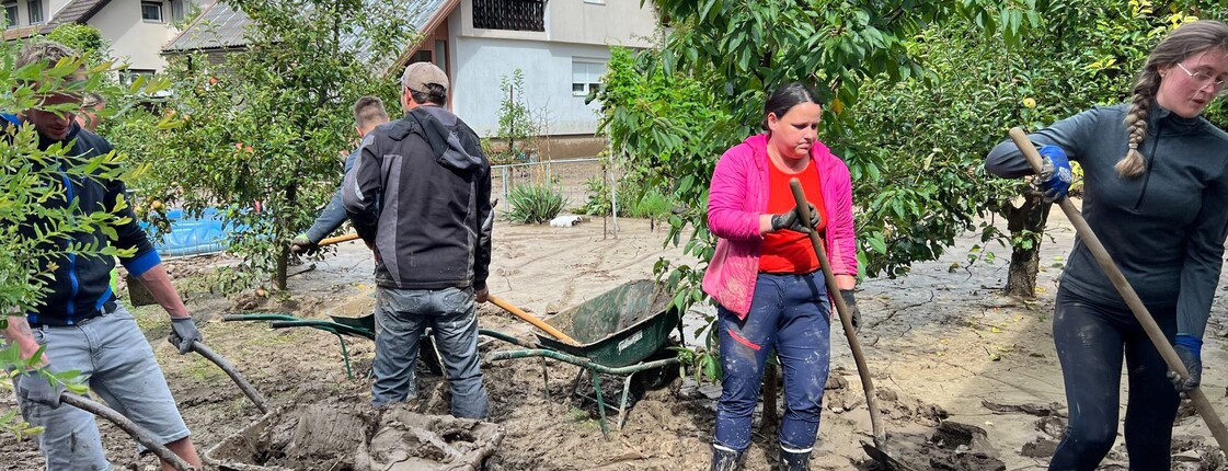 Freiwillige mit Schaufeln, sie entfernen Schlamm nach Hochwasser