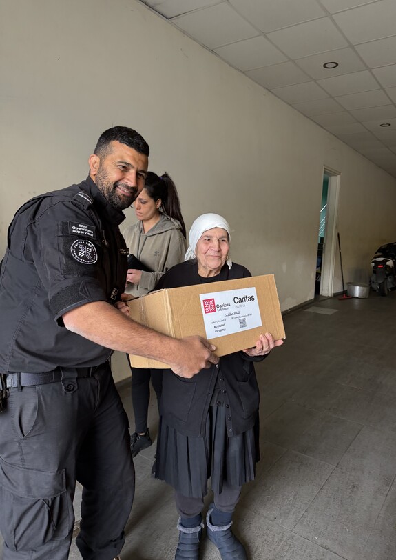 Eine Frau ist glücklich, weil sie ein Carepaket von einem Helfer bekommt.