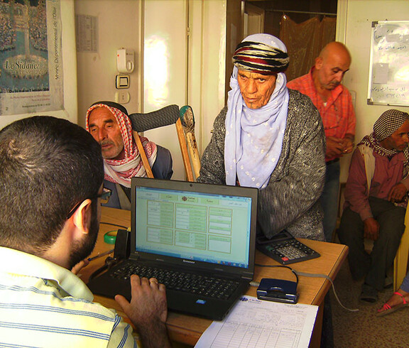 Ein Mann arbeitet am Computer, 3 Männer stehen davor