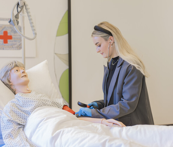 Eine junge Frau über an einer Pflegepuppe