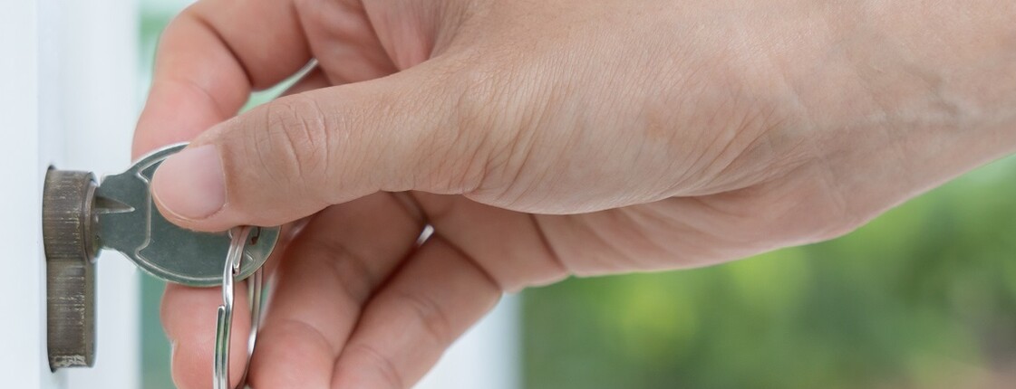Hand sperrt mit Schlüssel Tür auf