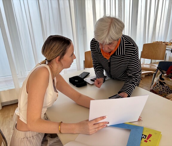 Eine junge Frau erklärt einer Seniorin das Smartphone