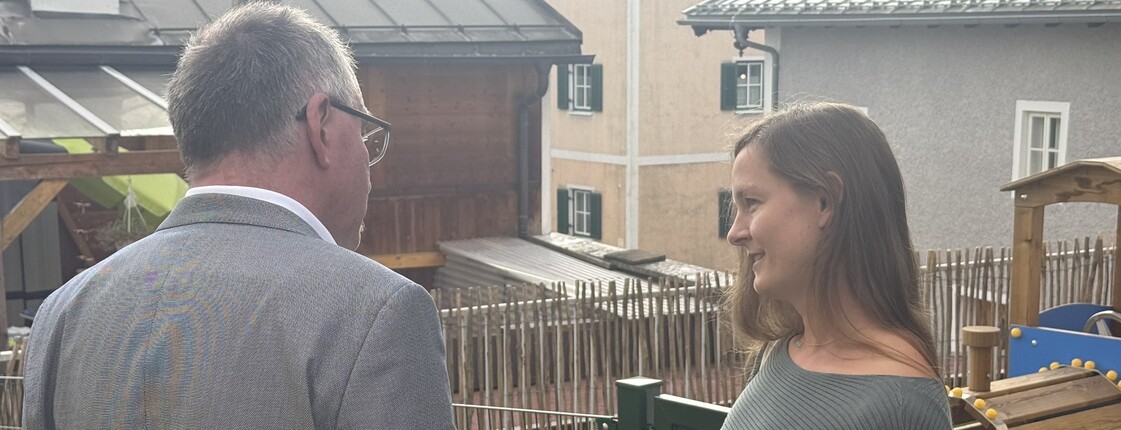 Ein Mann und eine Frau sprechen im Garten von einem Kindergarten