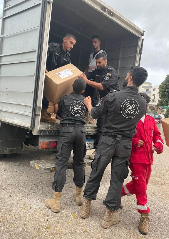 Helfer laden aus einem LKW Hilfspakete aus
