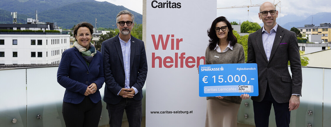 4 Personen halten einen Spendengutschein mit 15.000 Euro in der Hand
