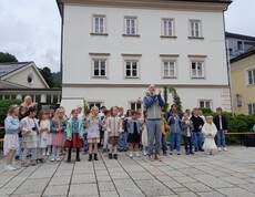 Eine Gruppe Kinder singt im Chor vor der Schule