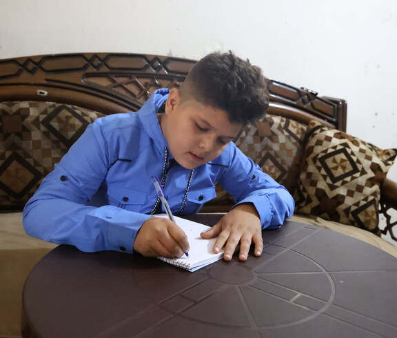 Ein Junge schreibt in ein Heft