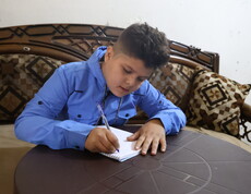 Ein Junge schreibt in ein Heft