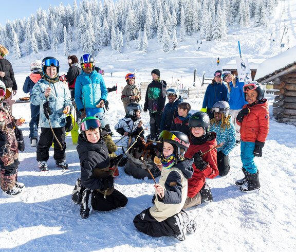 Eine Gruppe Kinder im Schnee beim Snowboardlernen
