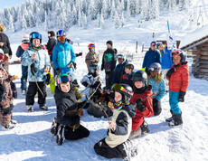 Eine Gruppe Kinder im Schnee beim Snowboardlernen
