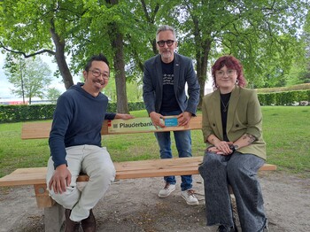 Drei Menschen bei einer Parkbank