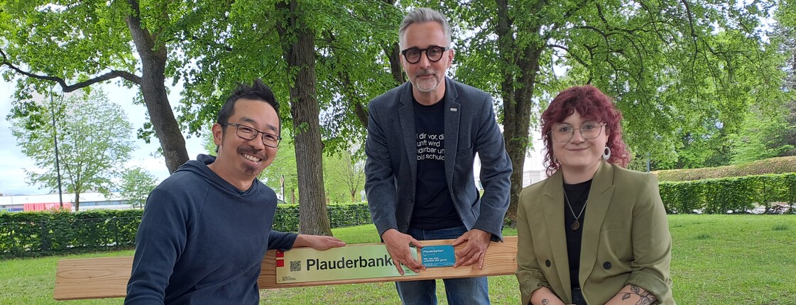 Drei Menschen bei einer Parkbank