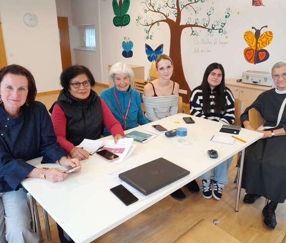 Sechs Menschen sitzen an einem Tisch