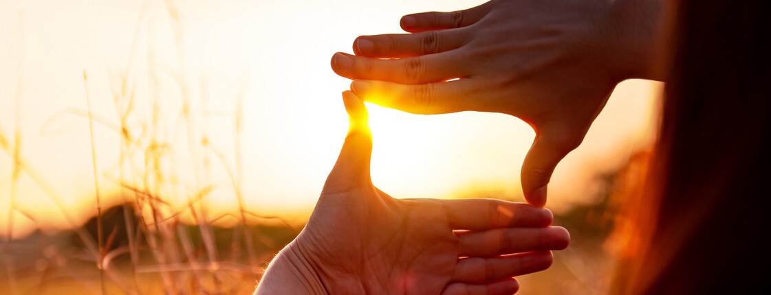 Zwei Hände formen einen Rahmen, indem sich die Sone bündelt.