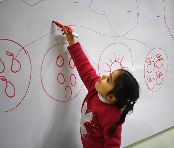 Ein Mädchen zeichnet an einer Tafel