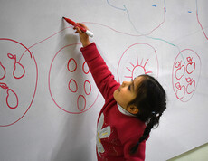 Ein Mädchen zeichnet an einer Tafel