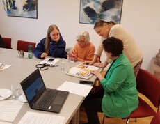 Eine Schülerin und drei Seniorinnen an einem Tisch