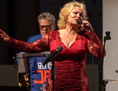 Eine Frau im roten Kleid singt auf einer Bühne