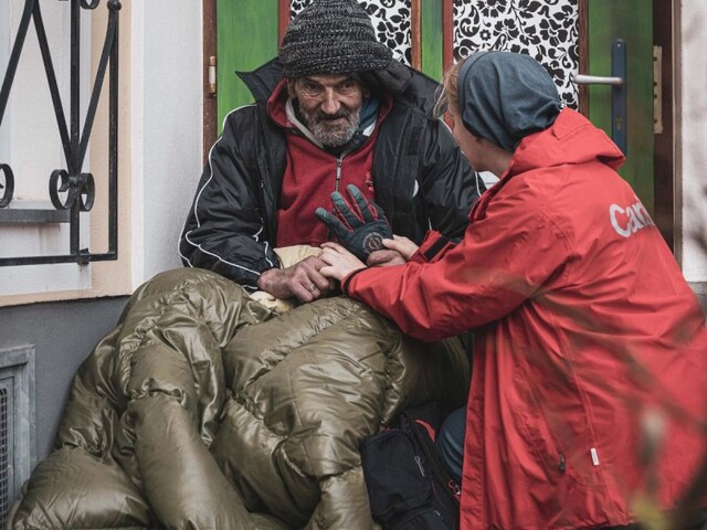 Obdachdachloser im Schlafsack mit Street Workerin