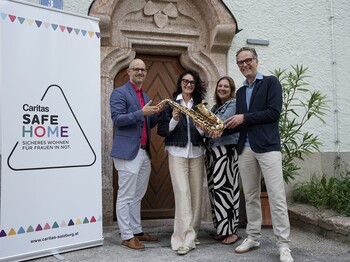 2 Frauen und 2 Herren mit einem Instrument vor dem Safe Home Hallein