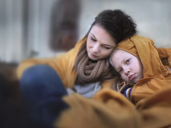 Rund jede fünfte Frau in Österreich ist armuts- oder ausgrenzungsgefährdet. Ukrainian immigrants mother with daughter with luggage waiting at train station wrapped in blanket