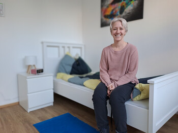 Eine Frau sitzt auf einem Bett und lacht