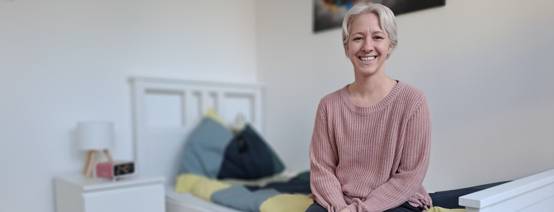 Eine Frau sitzt auf einem Bett und lacht