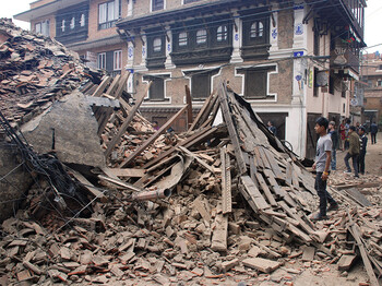 Ein Mann in Nepal steht vor einem zerstörten Haus