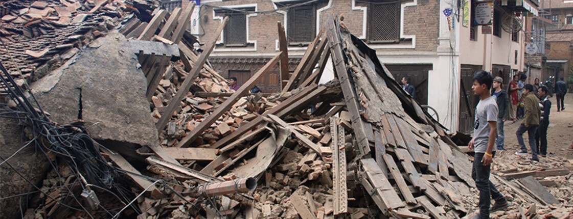 Ein Mann in Nepal steht vor einem zerstörten Haus