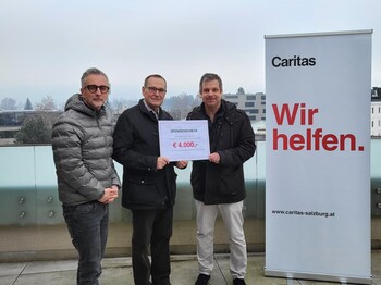 Drei Männer mit einem Schild, auf der die Spendensumme steht