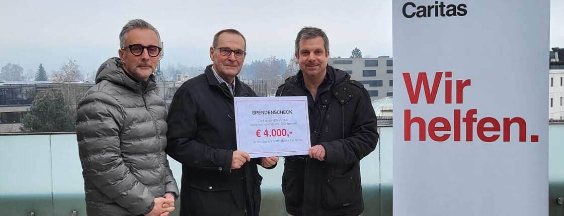 Drei Männer mit einem Schild, auf der die Spendensumme steht