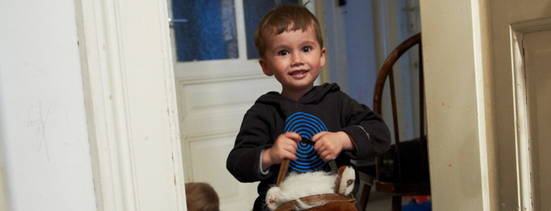 Kleiner Bub auf Schaukelpferd wartet auf die Christkindlaktion