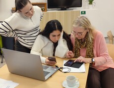 2 Schülerinnen erklären einer Seniorin das Smartphone