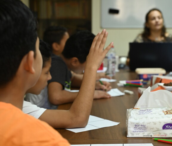 Kinder werden in einer Klasse unterrichtet und heben die Hand.