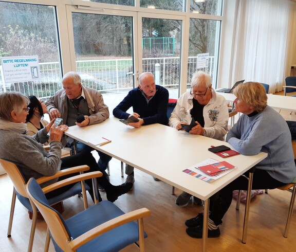 Eine Runde Senior*innen unterhält sich mit jungen Menschen