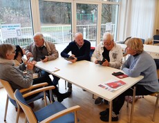 Eine Runde Senior*innen unterhält sich mit jungen Menschen