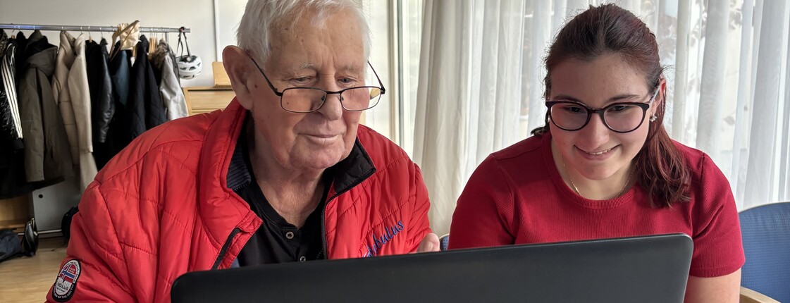 Eine junge Frau und ein älterer Mann arbeiten gemeinsam an einem Laptop