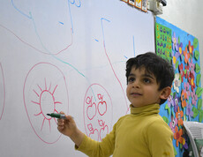 Ein kleiner Junge zeichnet an einer Schultafel