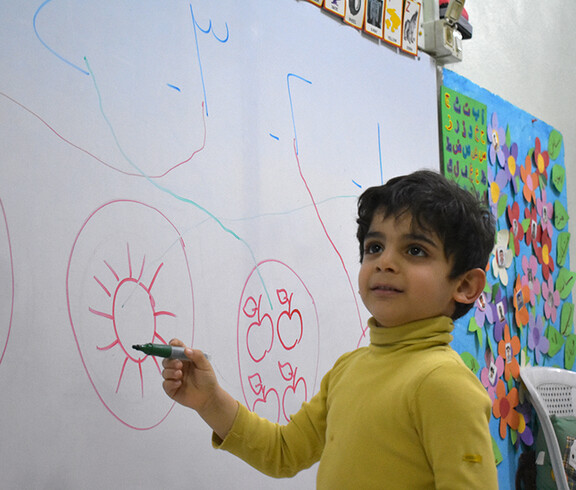 Ein kleiner Junge zeichnet an einer Schultafel