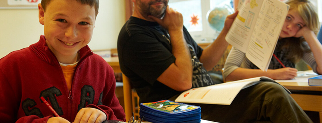 Zwei SchülerInnen und ein Lehrer der Allgemeinen Sonderschule im Caritas Dorf St. Anton im Klassenzimmer.