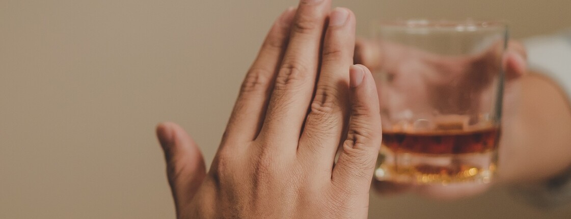 Eine Hand verweigert Glas mit Alkohol