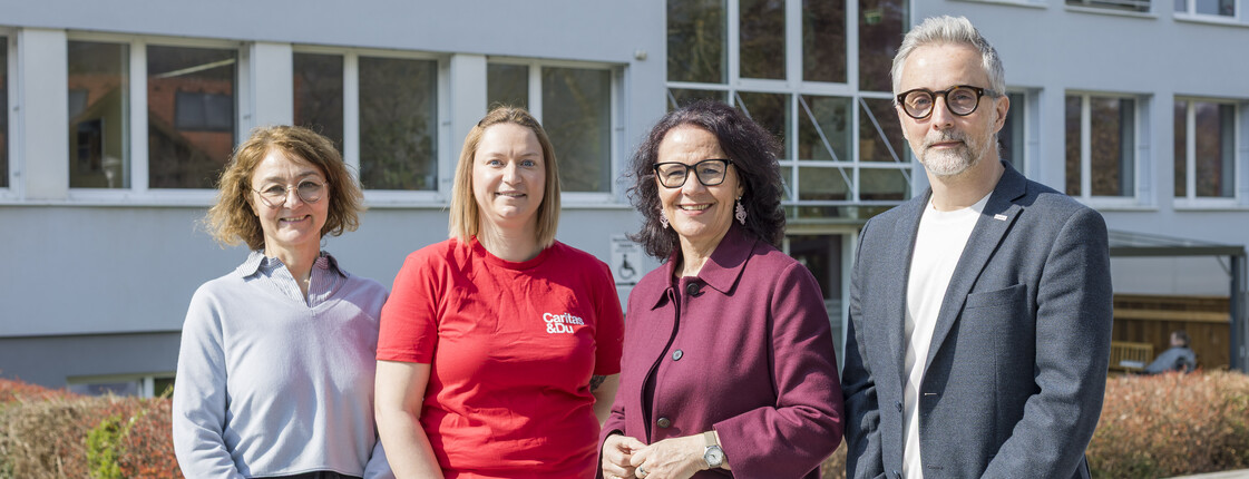 3 Frauen und ein Mann vor einer Schule