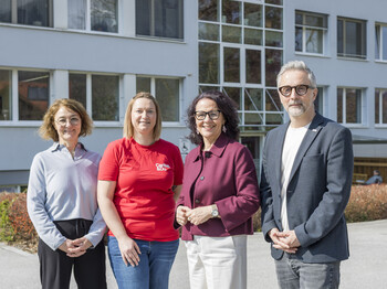 3 Frauen und ein Mann vor einer Schule
